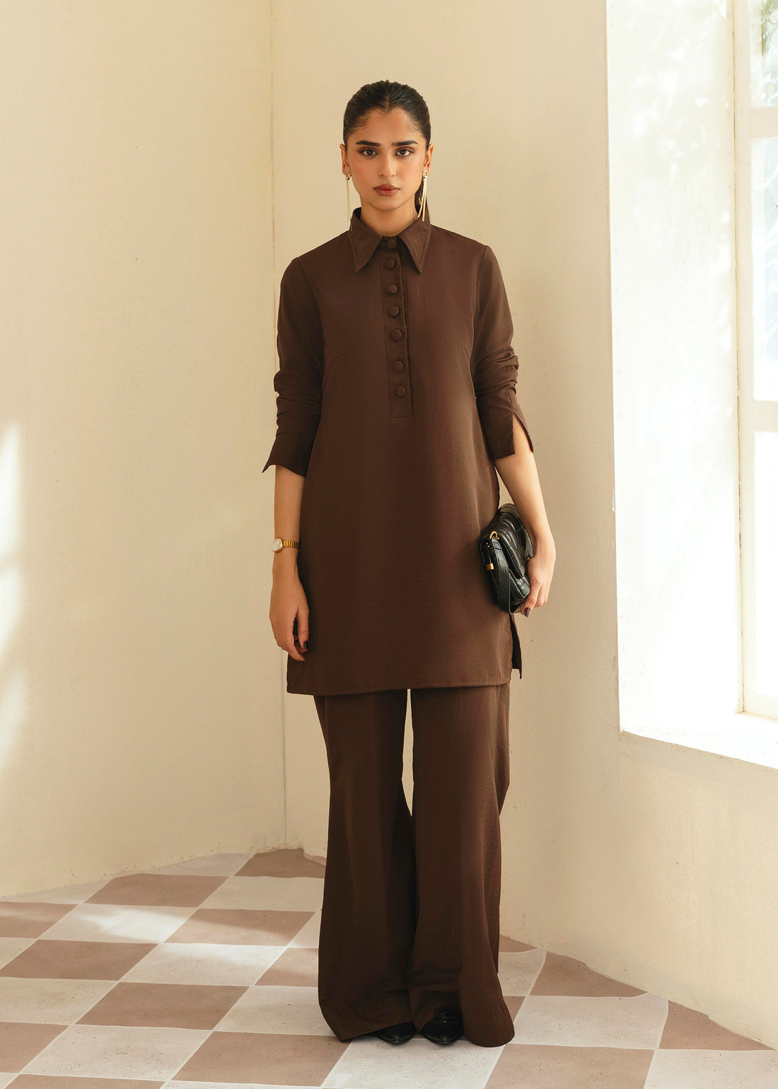 Woman wearing a brown outfit standing in a room with a window. - Mohar