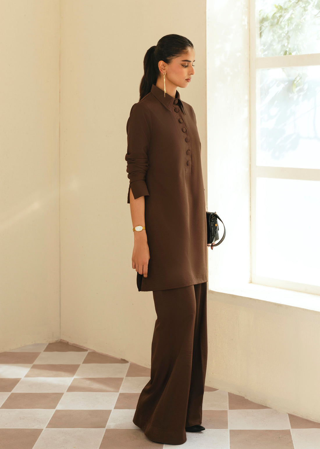 Woman wearing a brown outfit standing in a room with a window. - Mohar