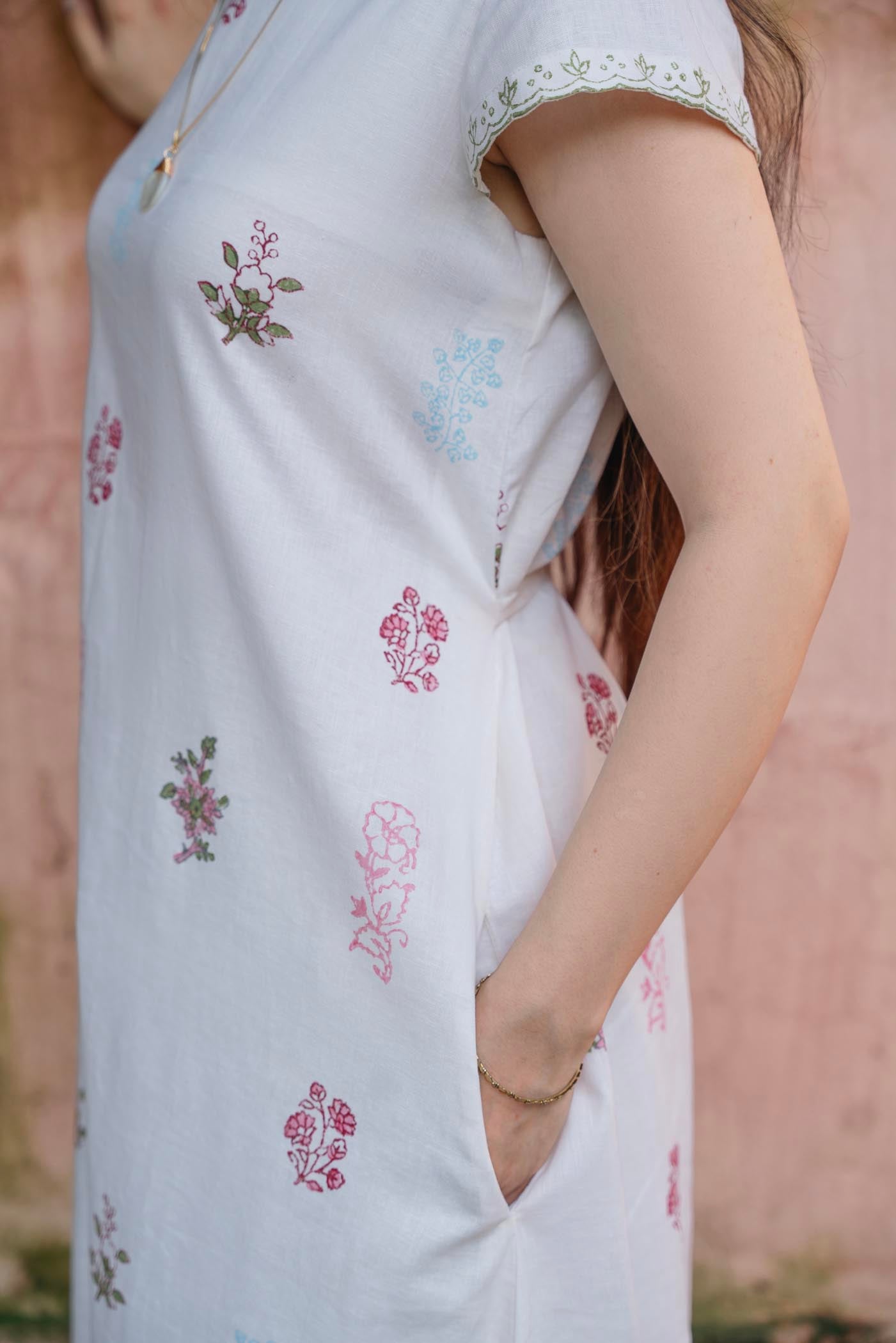 White dress with floral patterns worn by a women, blurred background